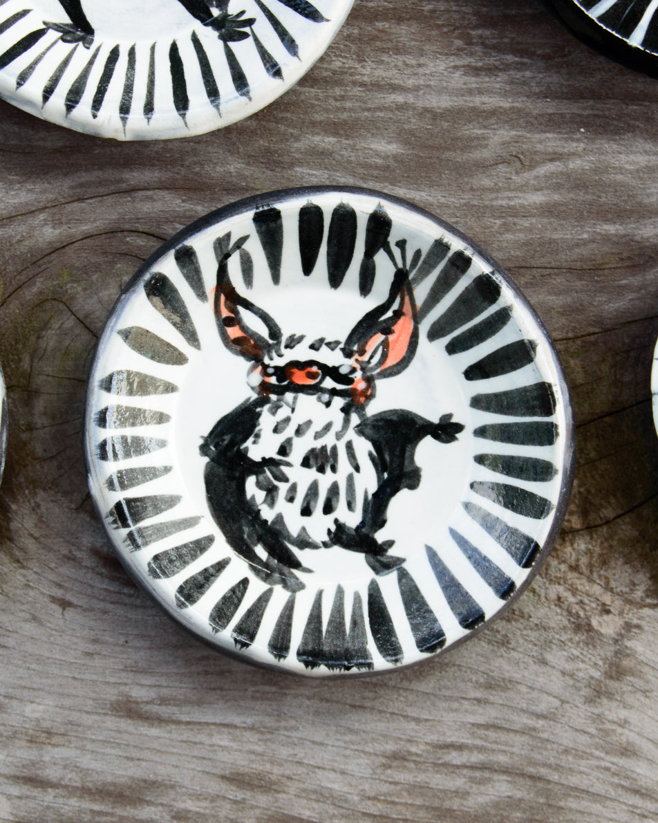 Ceramic plate with a black and white design of a bat on a wooden surface