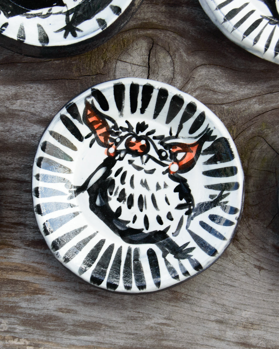 Ceramic plate with a black and white design of a bat on a wooden surface