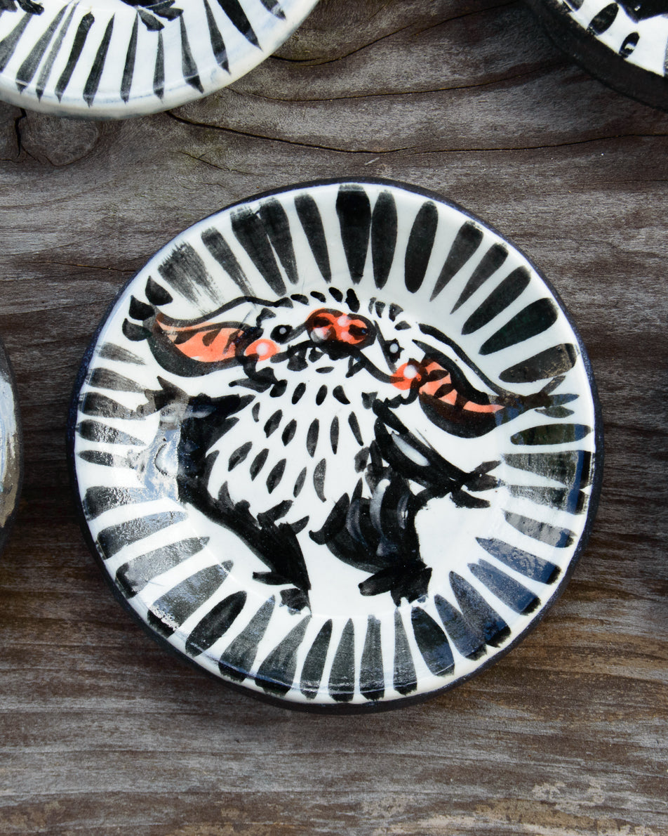 Ceramic plate with black and white painted bat design on a wooden surface