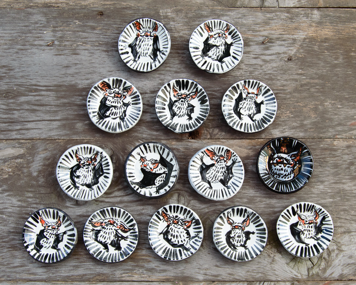 Set of twelve small ceramic plates with animal designs on a wooden surface