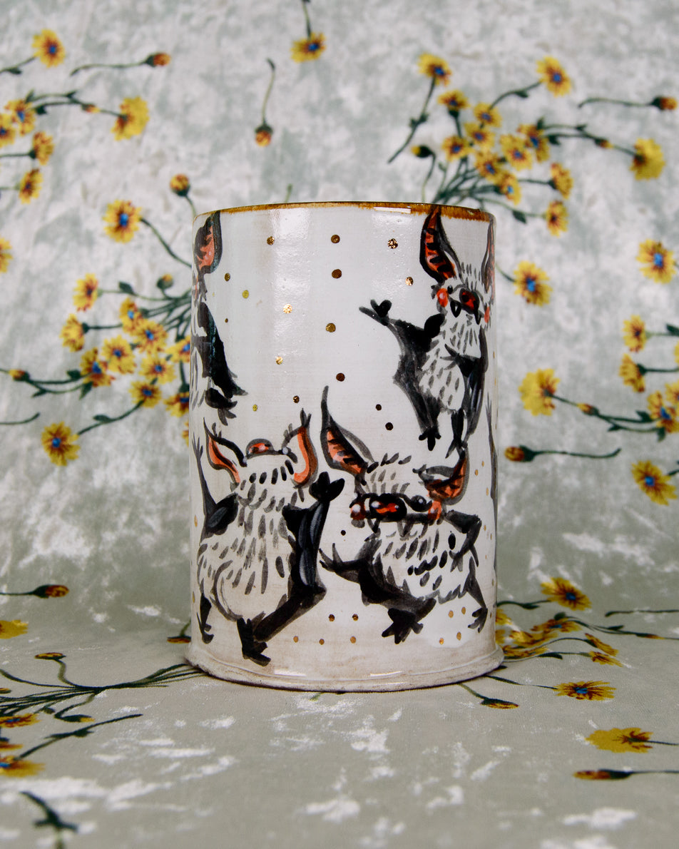 Ceramic tumbler with black and white bat design on a floral-patterned background