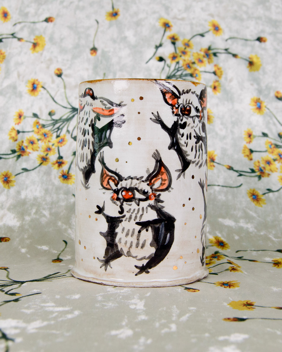 Ceramic cup with dancing bats designs on a floral background