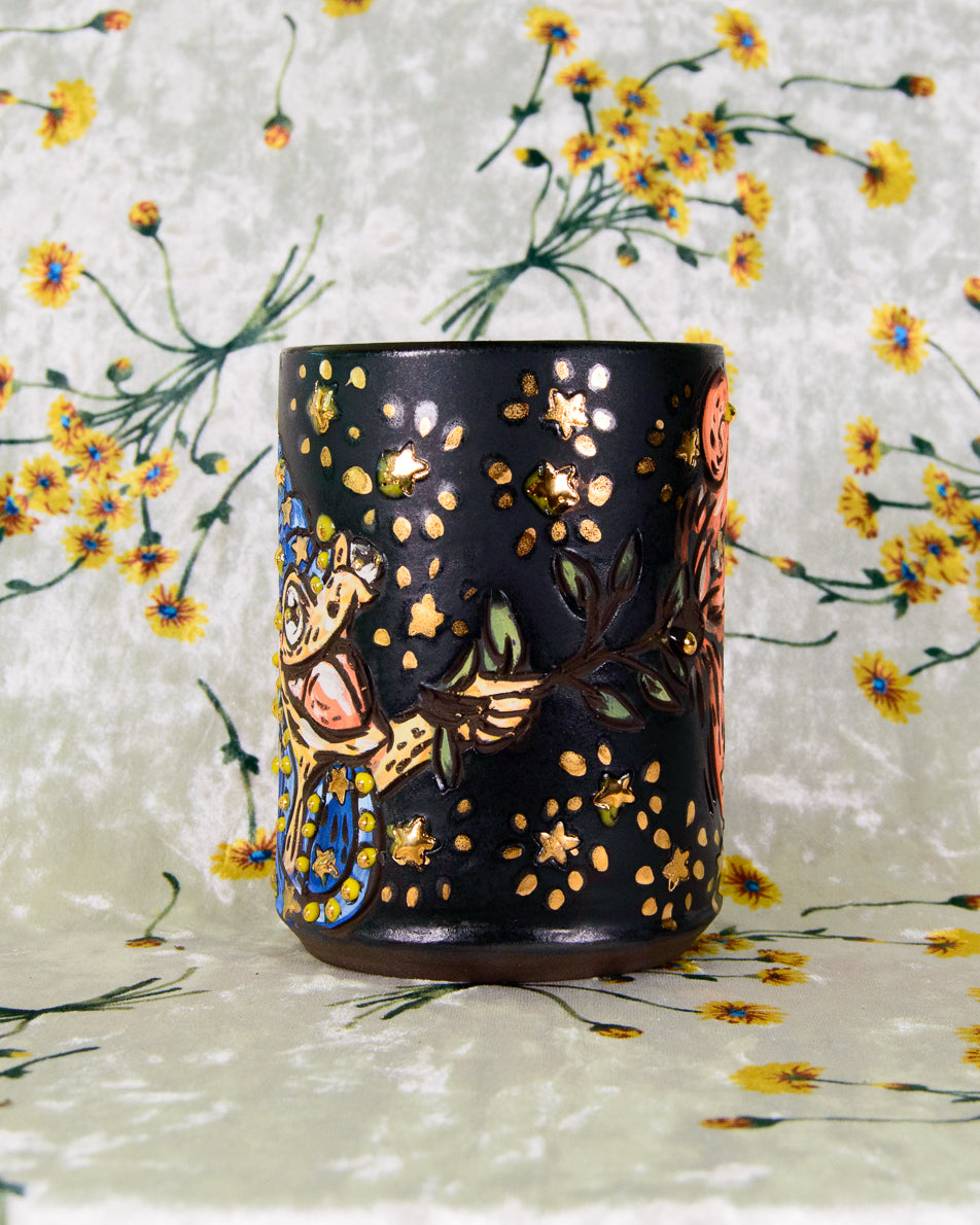 Black ceramic cup with a cartoon frog wizard design
