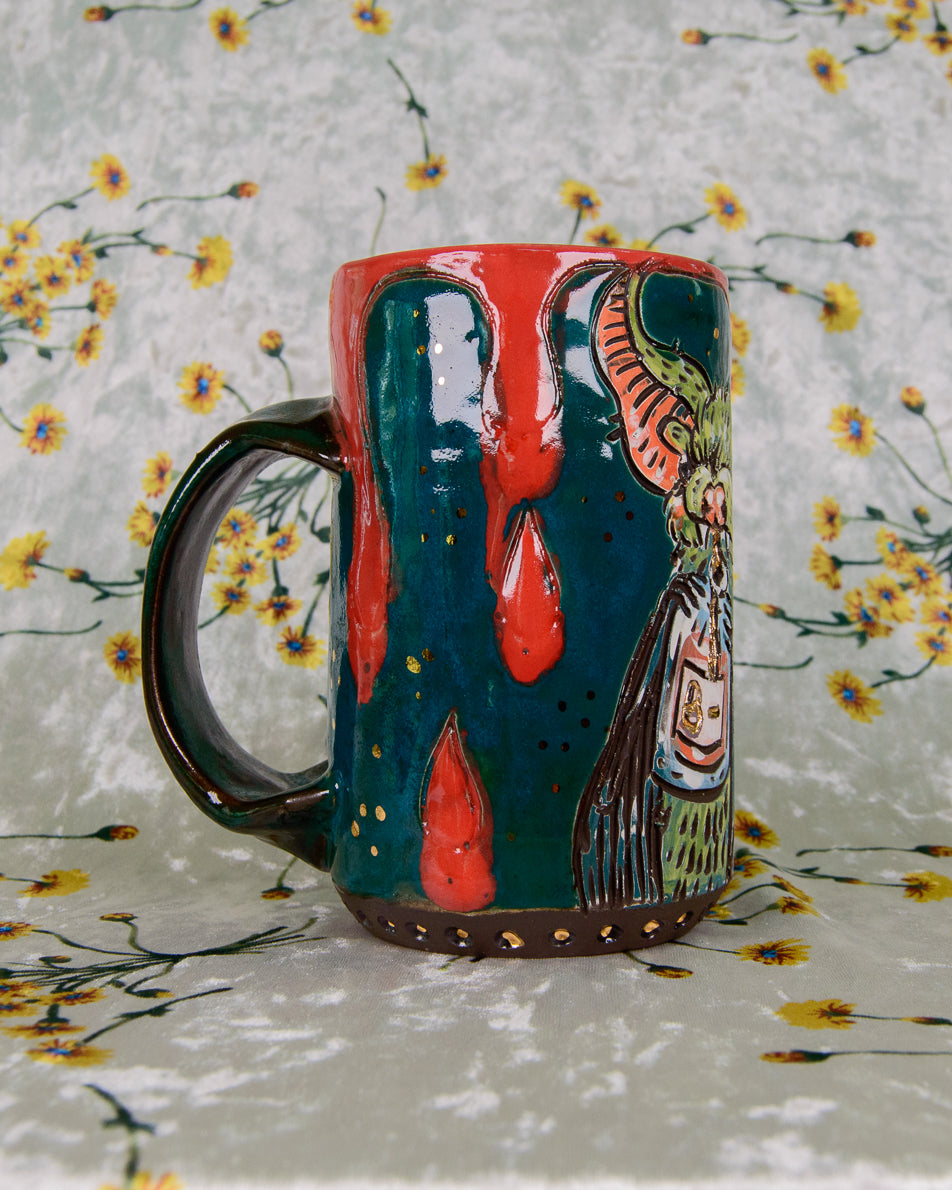 Blue stoneware mug with bright red blood drip designs and gold luster accents