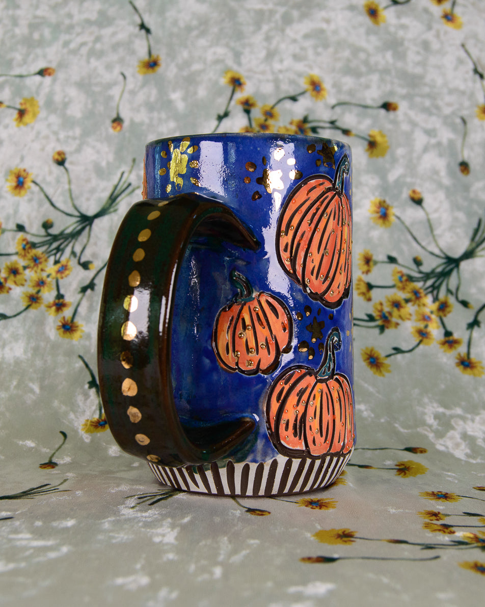 Ceramic mug with gold luster dots on the handle and a pumpkin design on a floral background