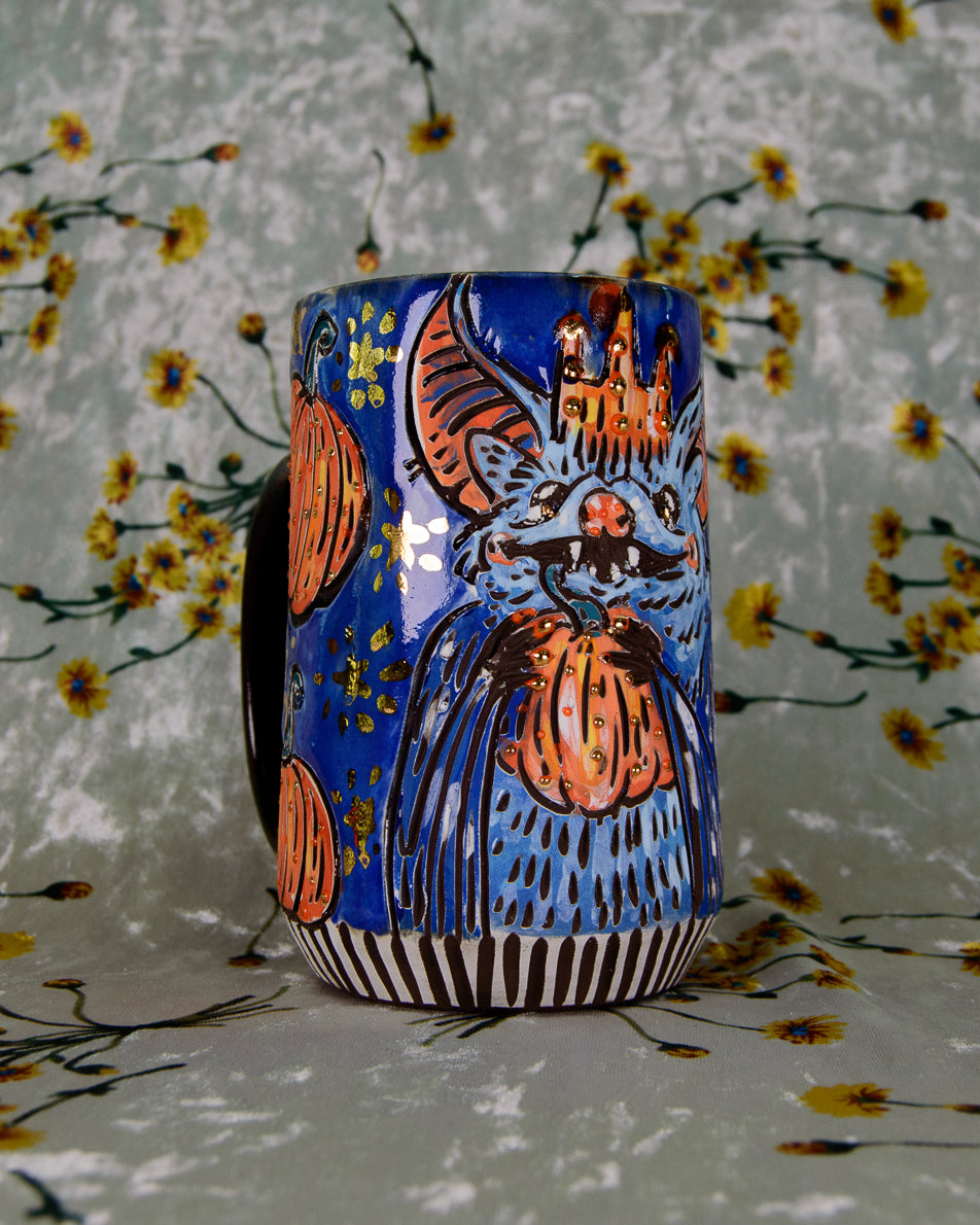Ceramic mug with a colorful bat design and shiny gold stars on a floral background