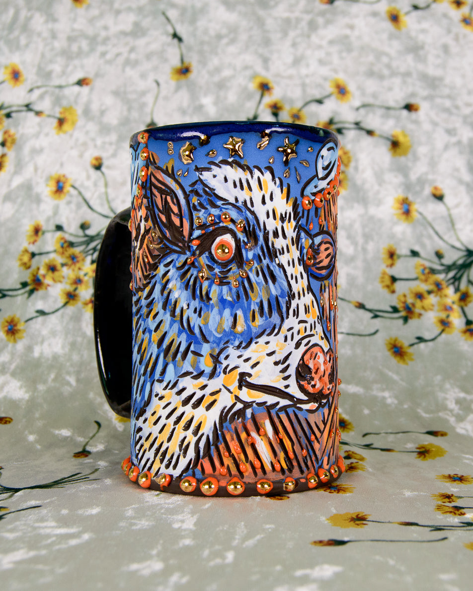 Ceramic mug with a colorful cow design and gold details