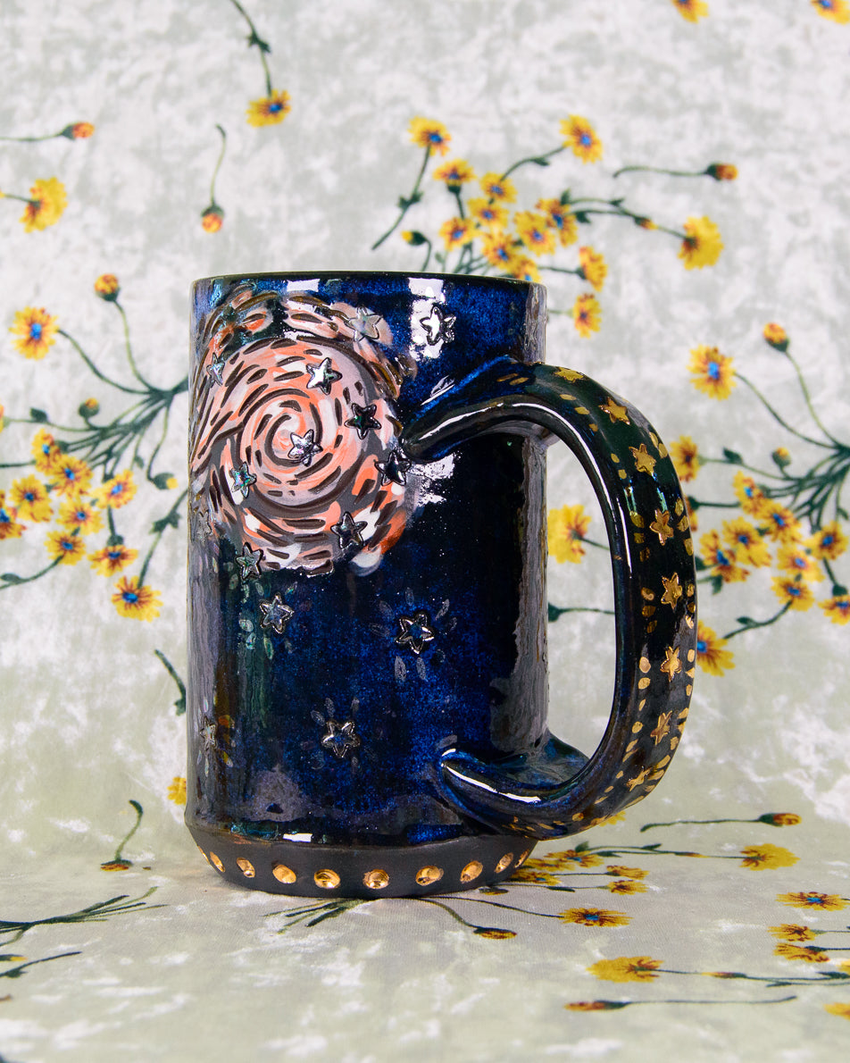 Blue ceramic mug with artistic gold star design on a floral background