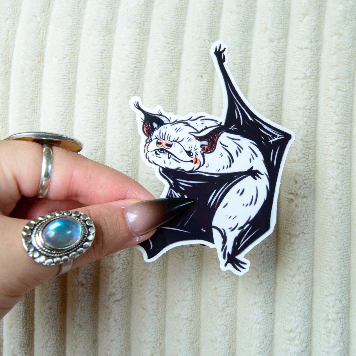 A sticker of a cute bat dancing ballet with pink accents against a beige background