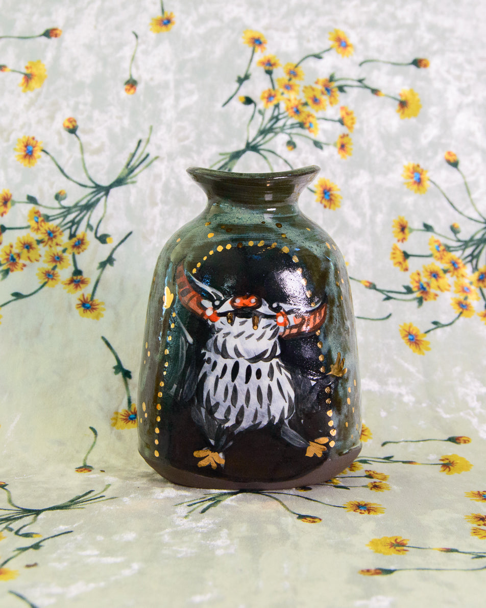 Decorative vase with dancing bat design on a floral background