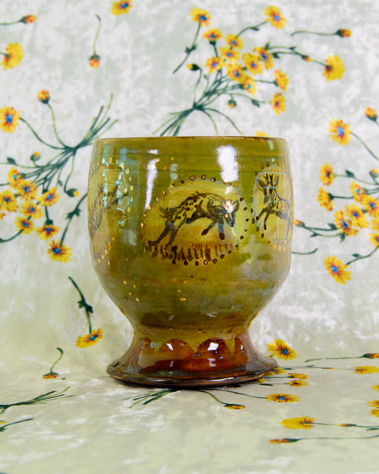 Ceramic cup with a painted deer design on a floral-patterned background