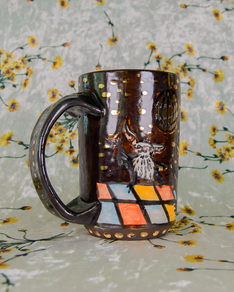 Brown ceramic mug with cartoon bat designs on a dance floor