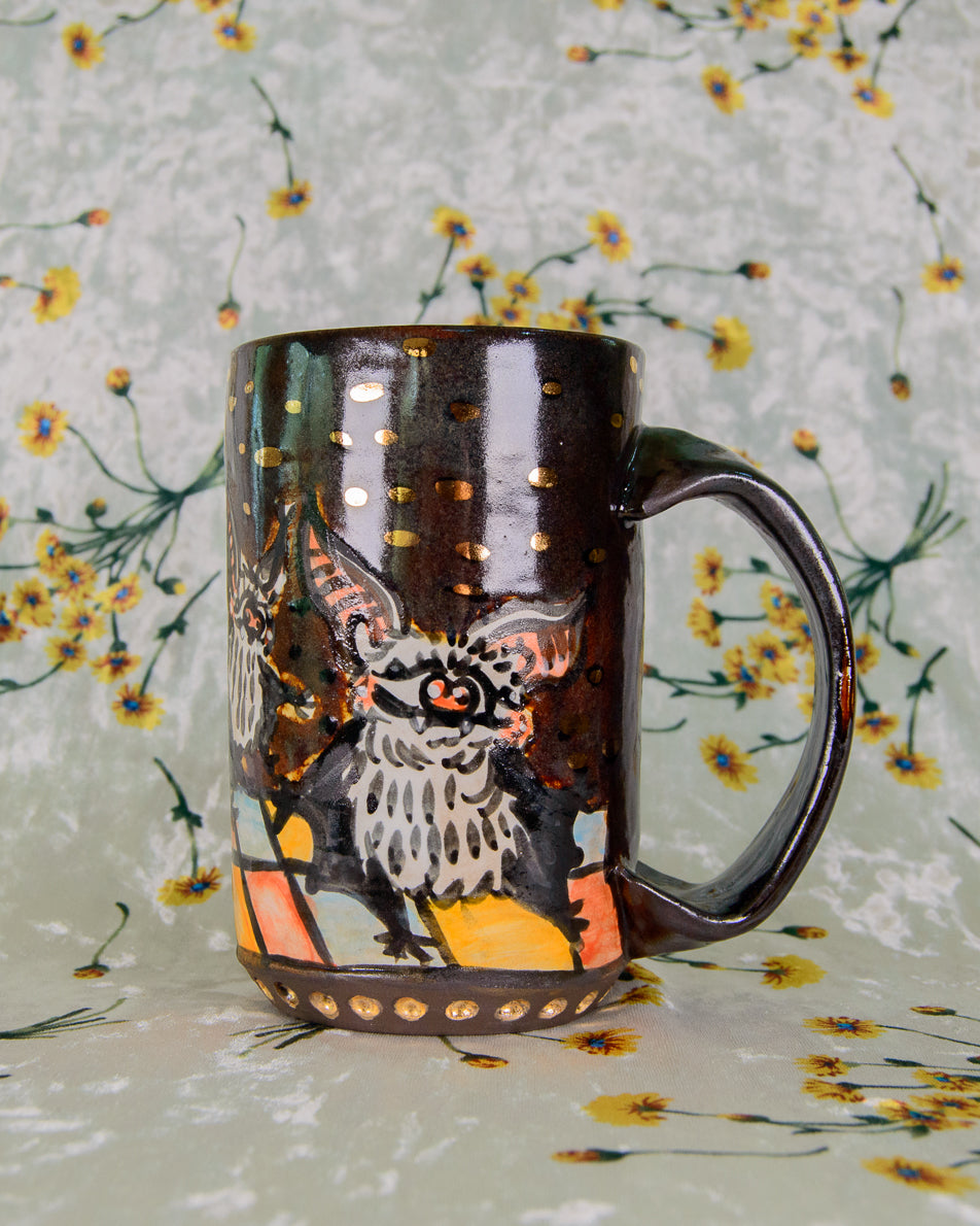Handmade ceramic mug with a dancing bat design and gold dots