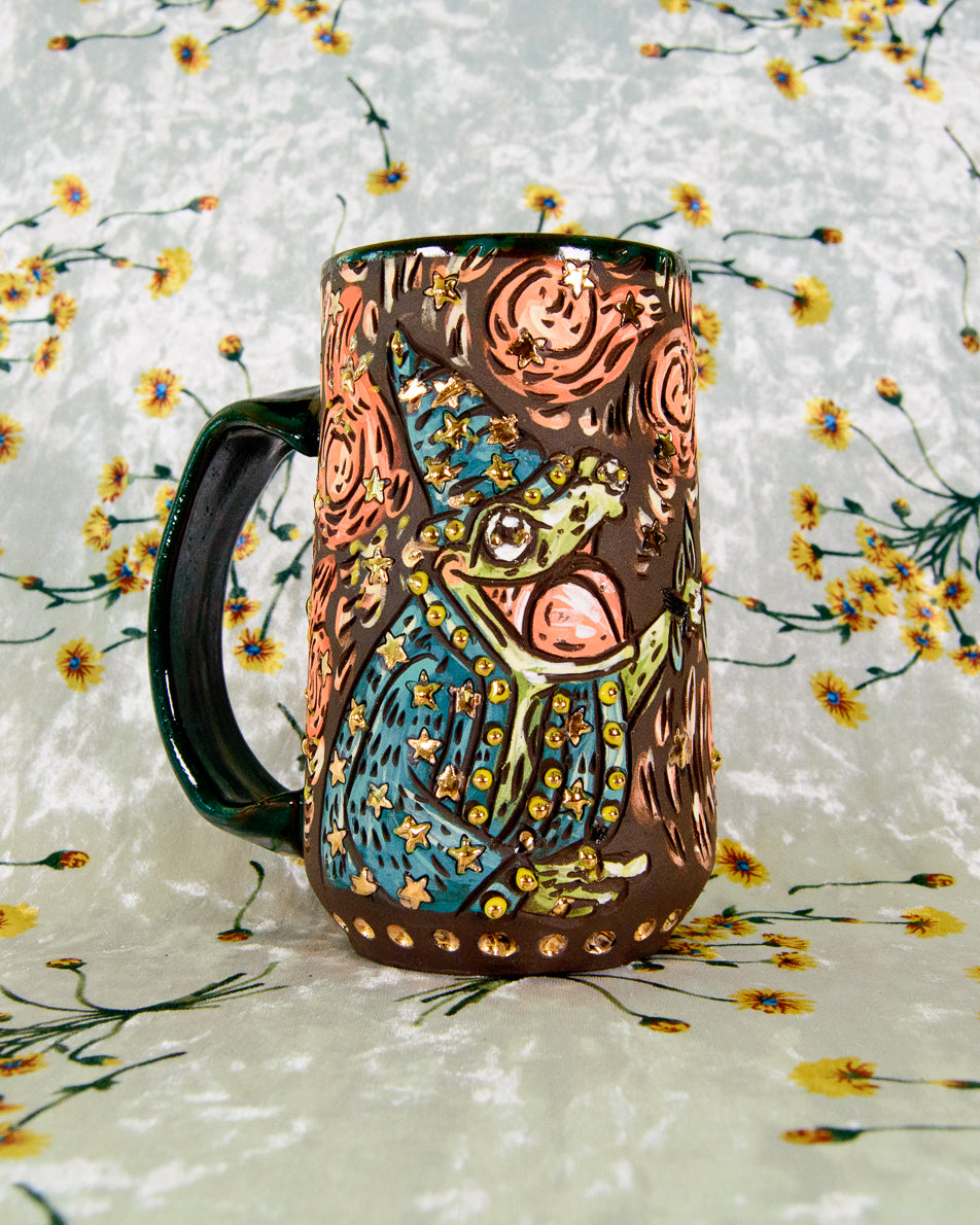Black stoneware ceramic mug with a cartoon frog wizard design