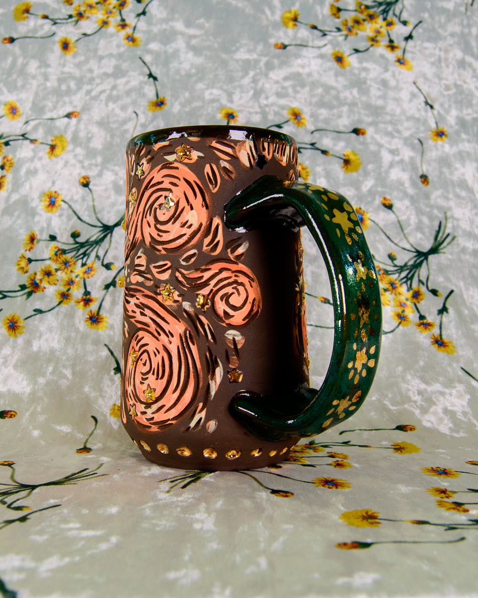 Black stoneware mug with cartoon magic swirl designs and gold luster shiny stars on a blue handle