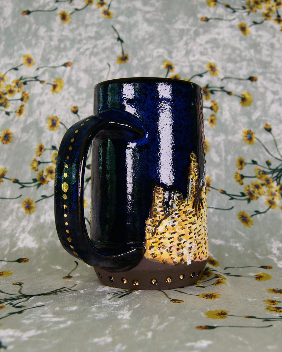 Dark blue mug with a gold coin pile design on a floral-patterned background