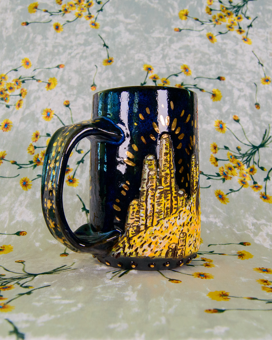 Black mug with yellow design on a floral-patterned background