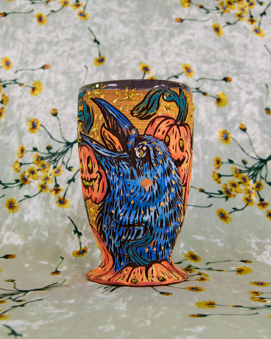 Intricate ceramic cup with a colorful crow and pumpkin design