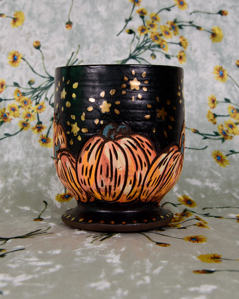 Black ceramic goblet cup with a pumpkin design and shiny gold stars