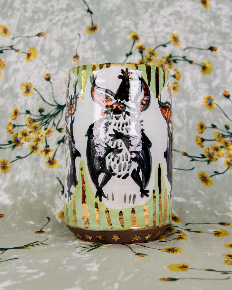 Ceramic mug with a black and white cartoon bat design and shiny gold details