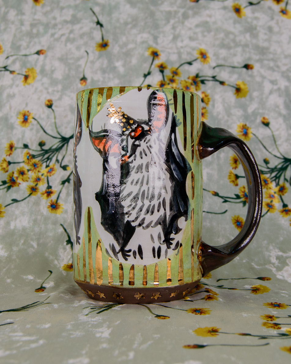 green black and white ceramic mug with a cute cartoon bat design and gold details