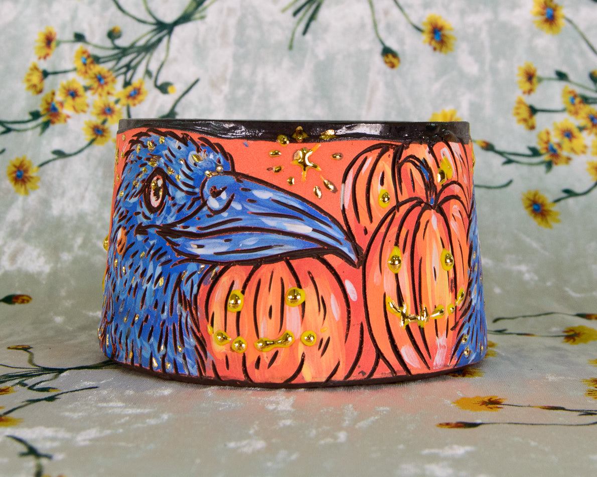 Colorful ceramic mug with crow and pumpkin design on a floral background