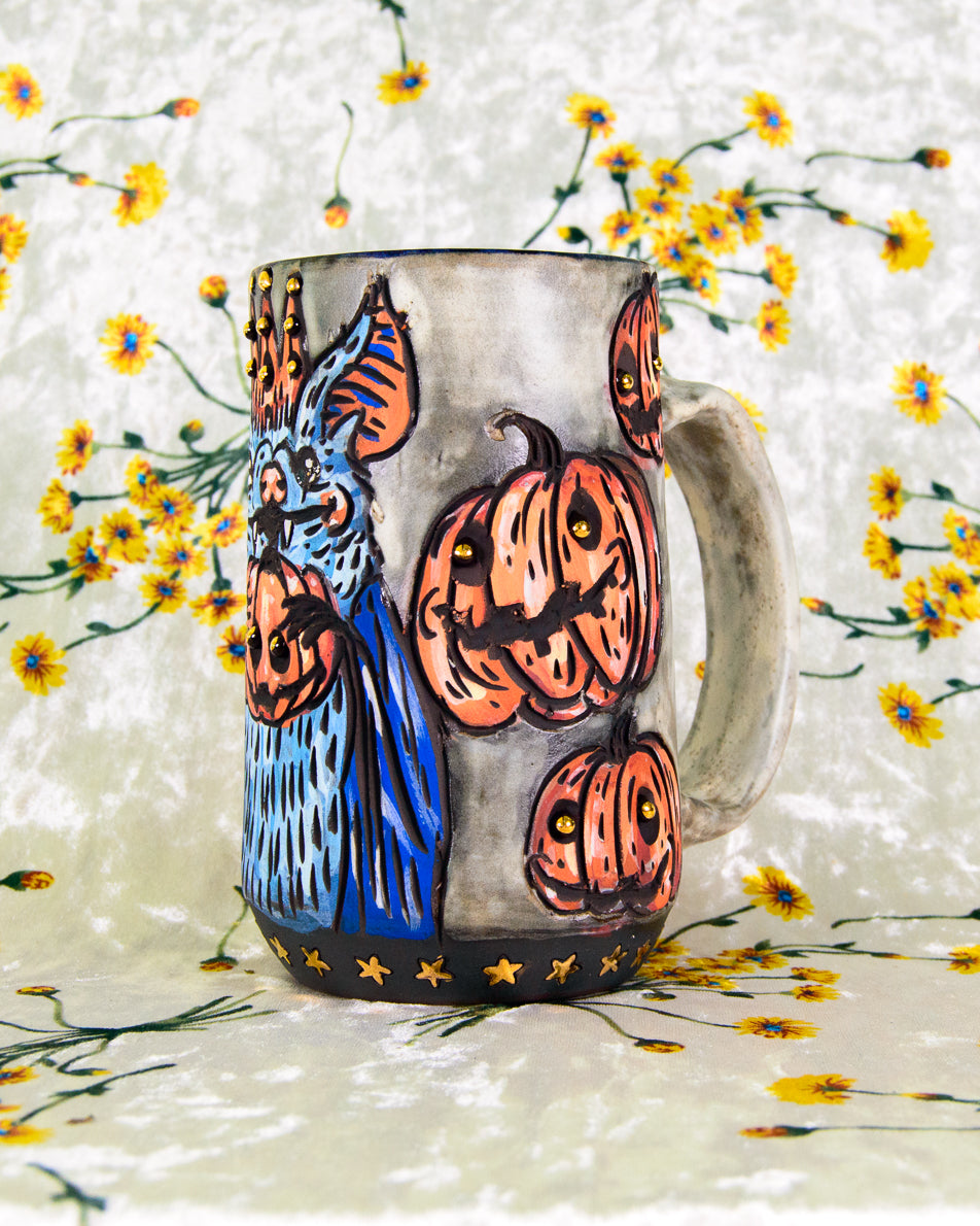 White mug with a colorful cartoon design of bats and halloween pumpkins