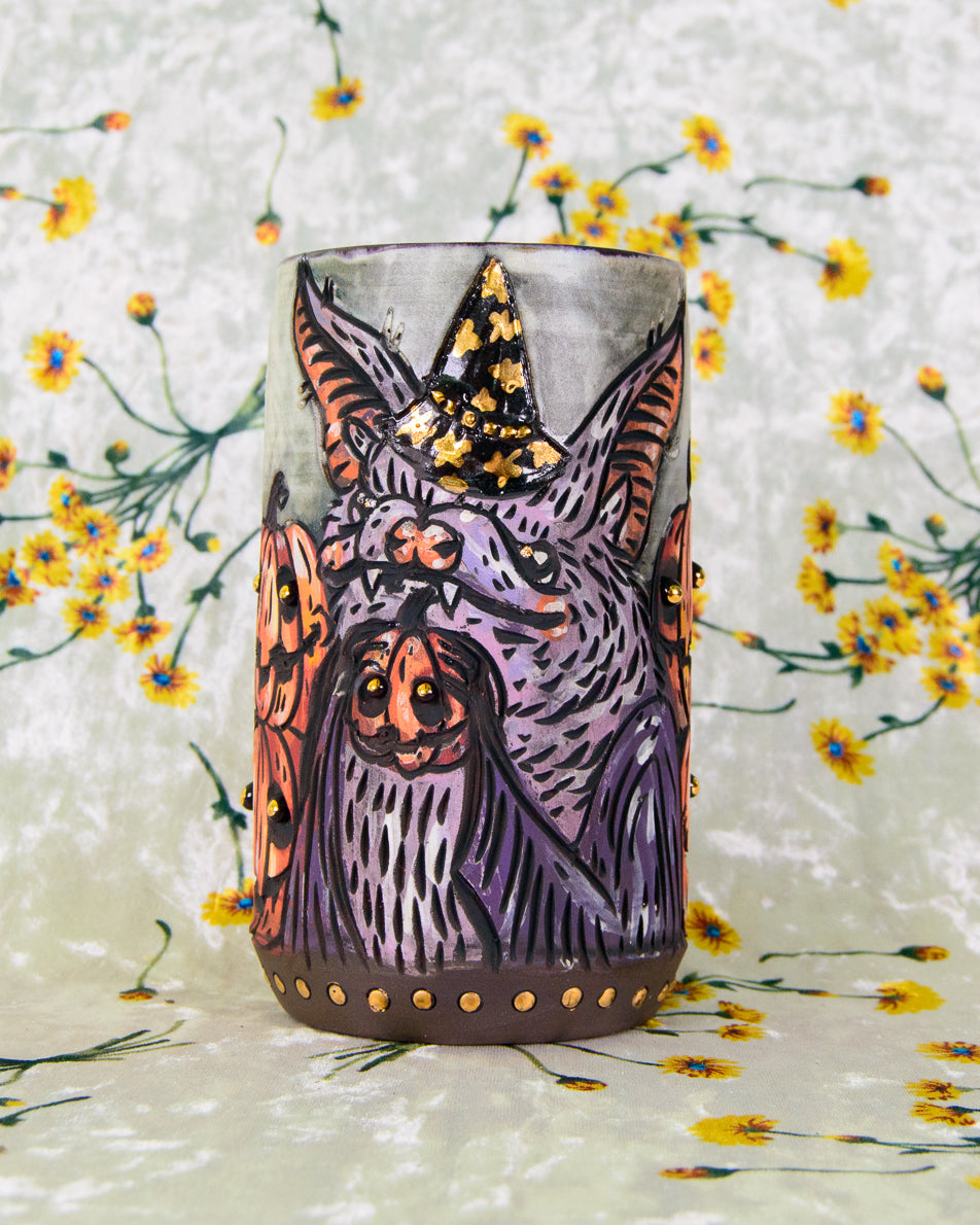 Ceramic mug with a halloween-themed design of a stylized bat with pumpkins