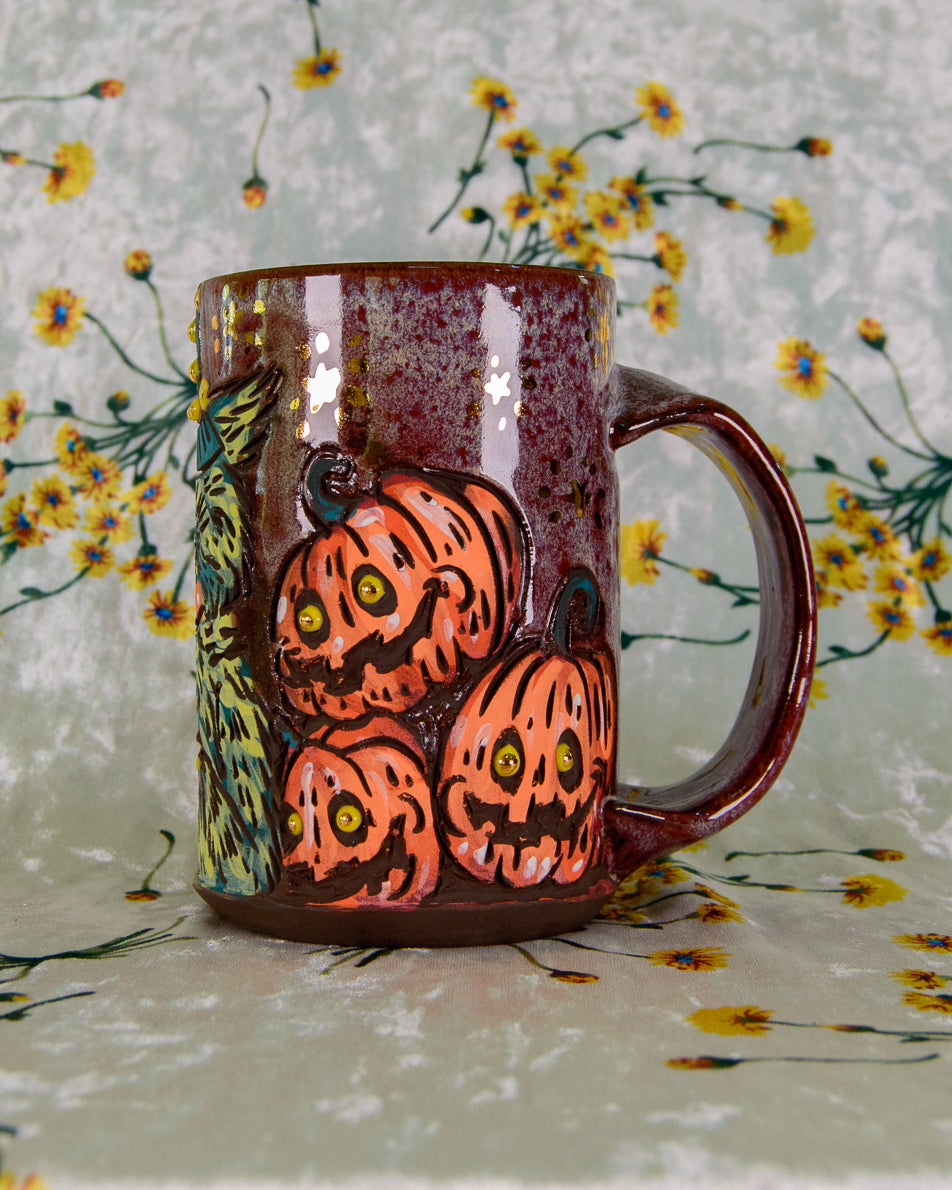 Ceramic mug with Halloween-themed design of pumpkins and stars on a floral background