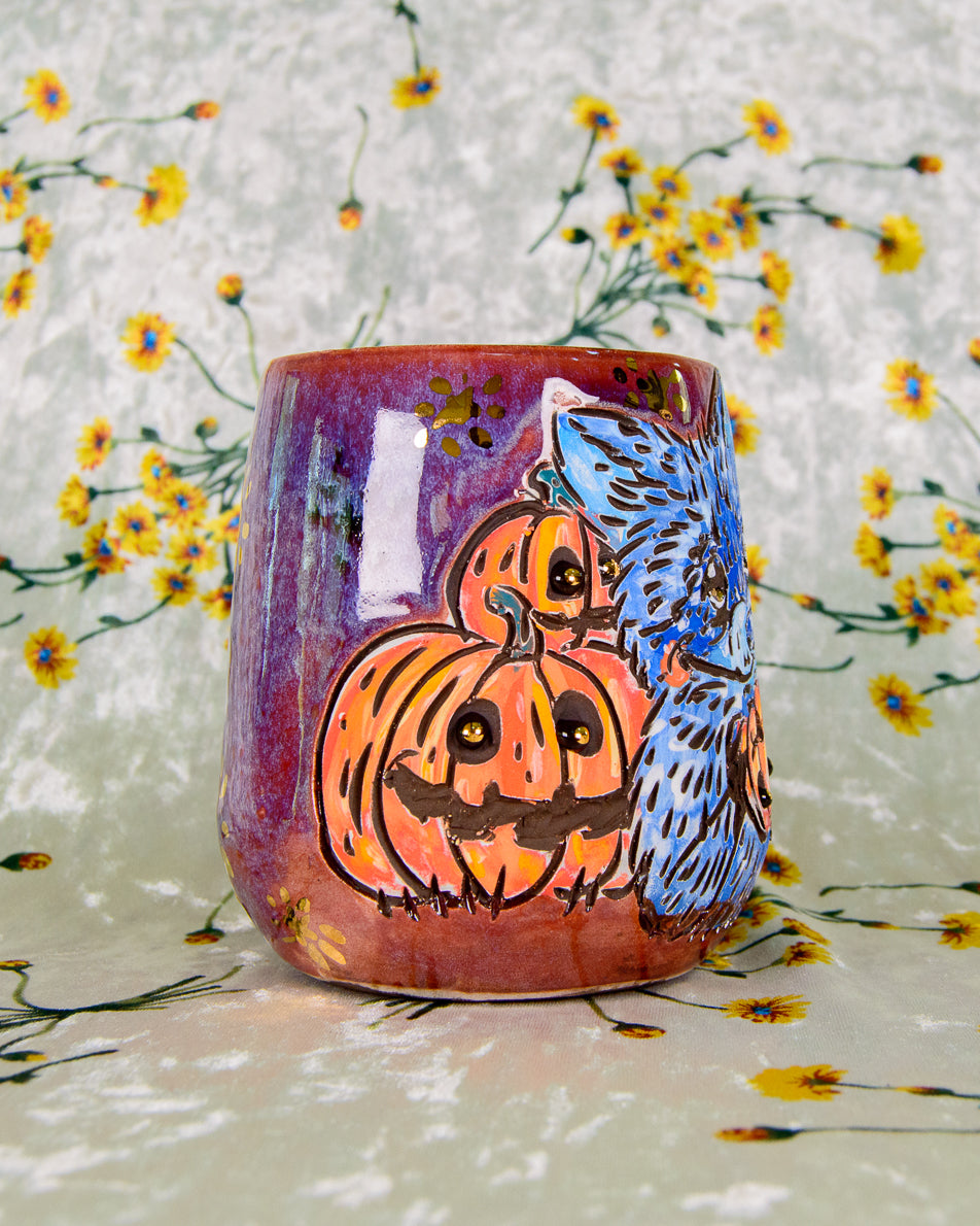 Ceramic tumbler with pumpkins and a raccoon design on a floral background