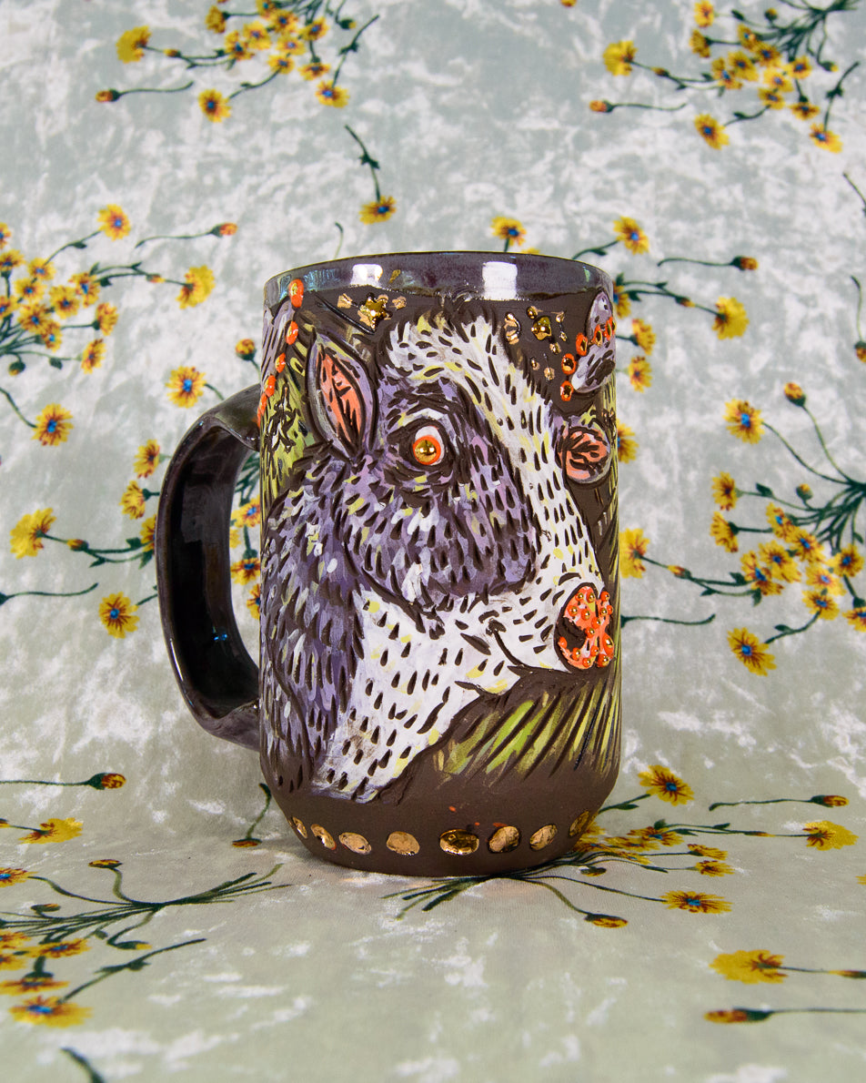Ceramic mug with a cartoon cow painted in purple, white, and orange colors