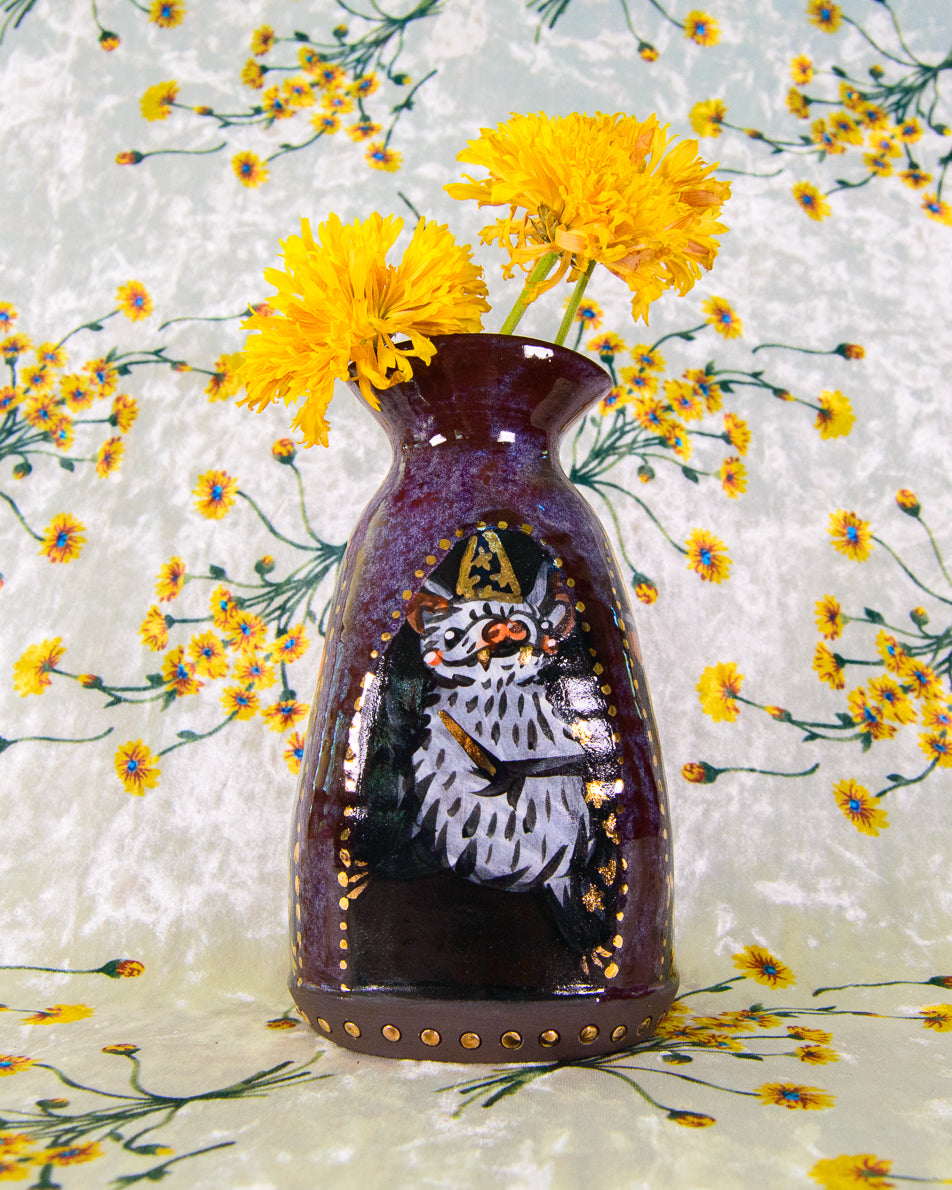 Decorative stoneware vase with a painted design of a wizard bat on a floral background