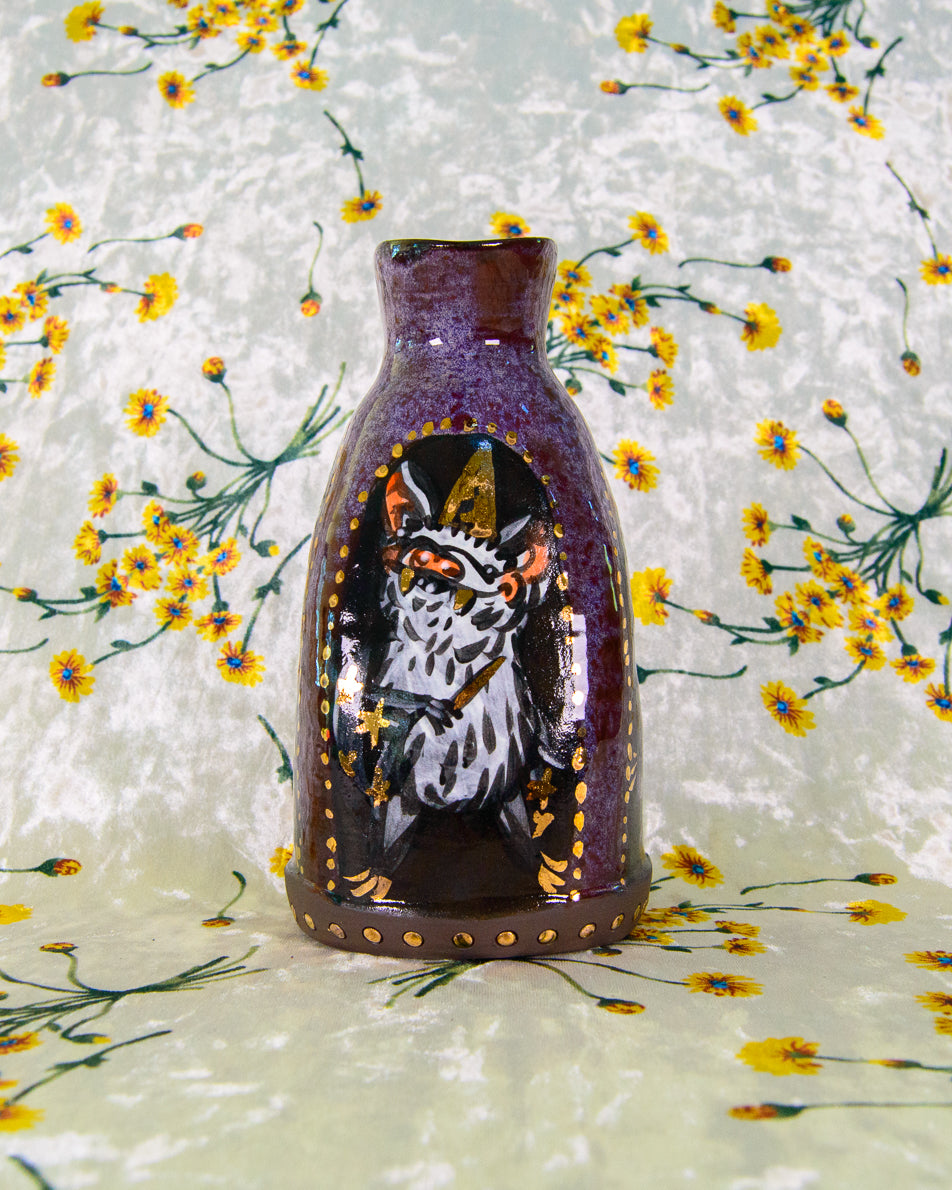 Decorative stoneware vase with a painted design of a wizard bat on a floral background