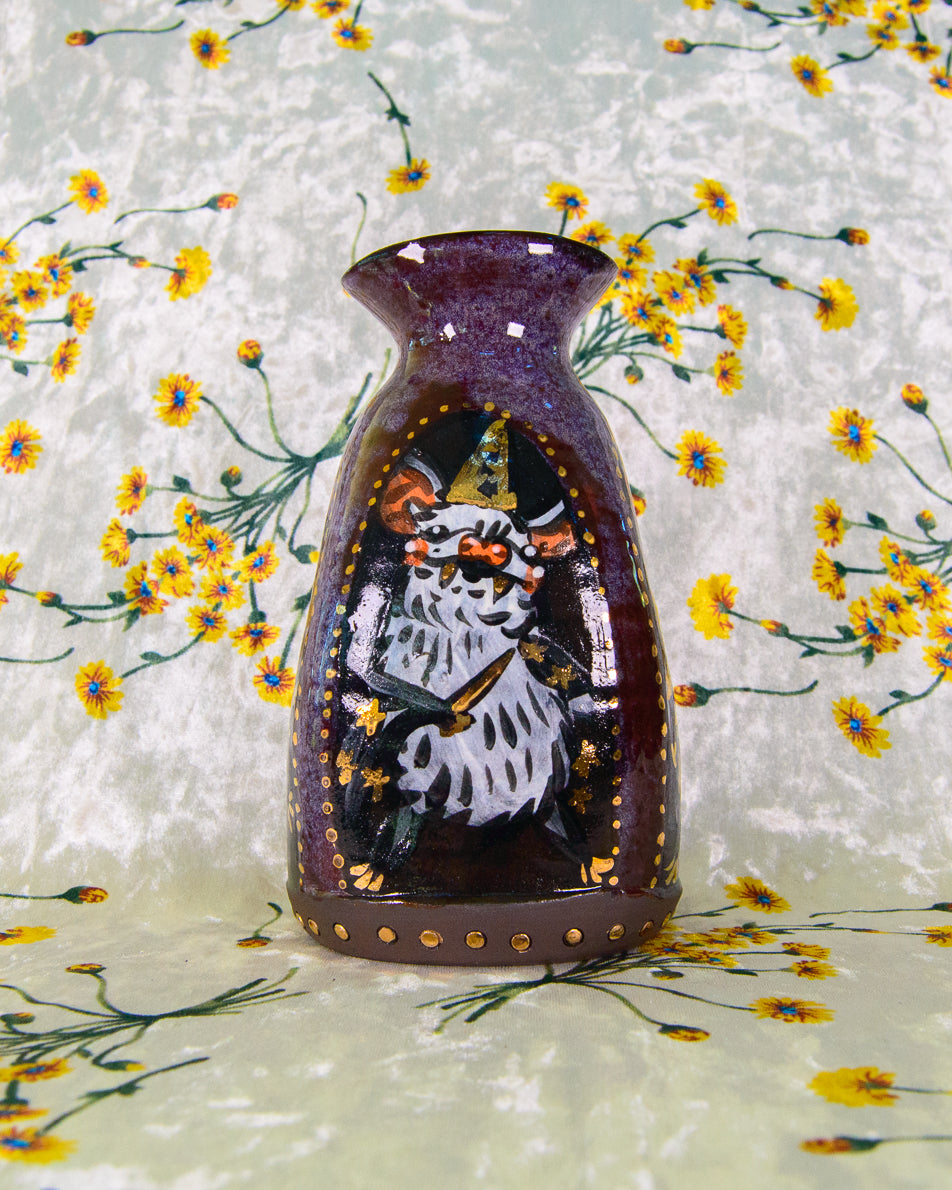 Decorative stoneware vase with a painted design of a wizard bat on a floral background