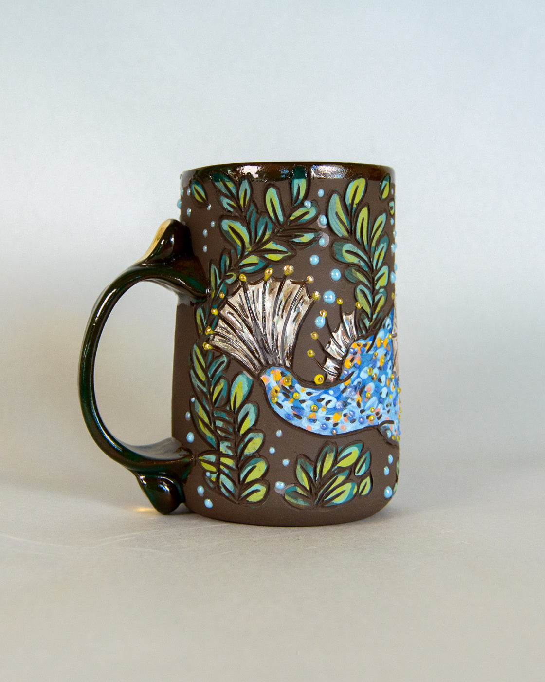 Decorative ceramic mug with nature-themed design on a light gray background