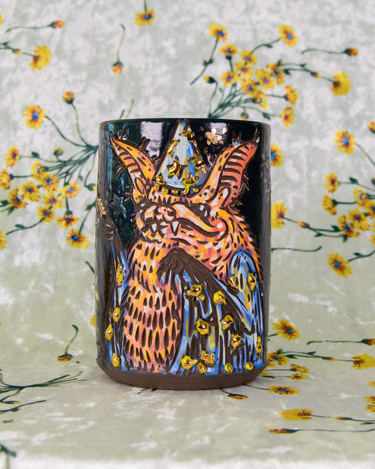 Ceramic cup with an orange and blue bat wizard design and gold luster shiny stars