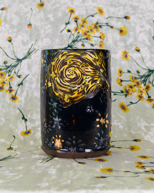 Black stoneware ceramic cup with starry night design on a floral background