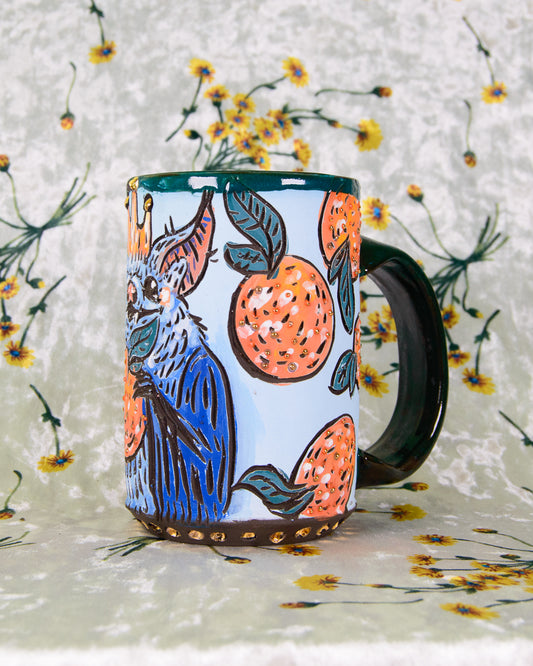 Hand made ceramic mug with cartoon orange fruit illustrations