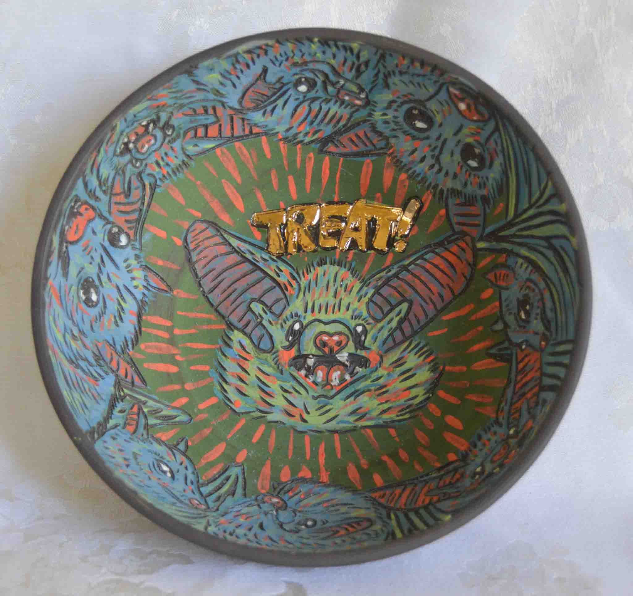 A ceramic candy bowl with a luster finish featuring a detailed illustration of bats in the center, with the word 'TREAT' written above.