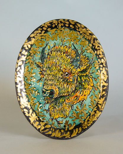 Decorative plate with a stylized bison head design on a plain background
