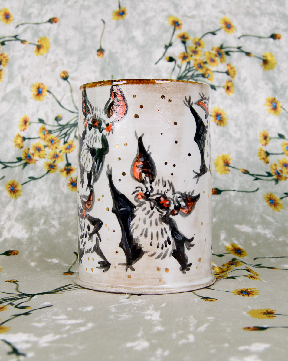Ceramic tumbler with bat designs on a floral background
