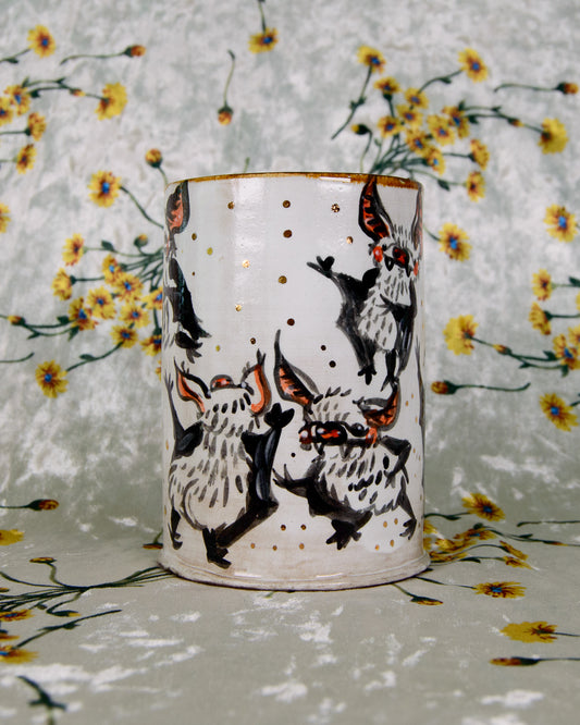 Ceramic tumbler with black and white bat design on a floral-patterned background