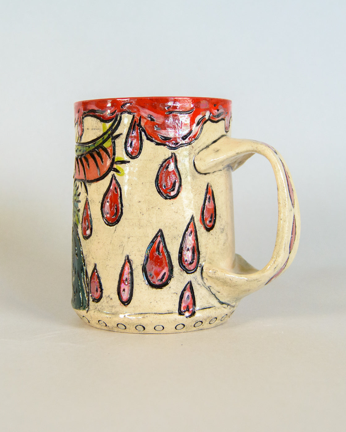 Ceramic mug with red blood drip pattern on a light gray background