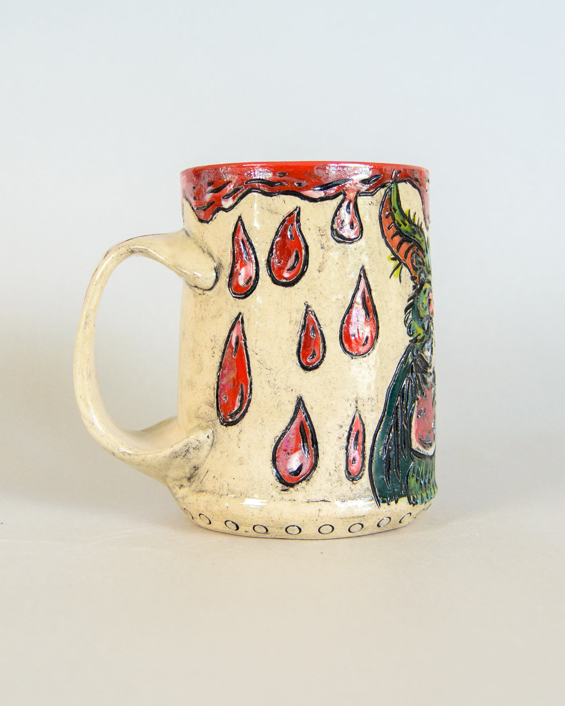 Ceramic mug with red blood drip designs and a bird on a white background