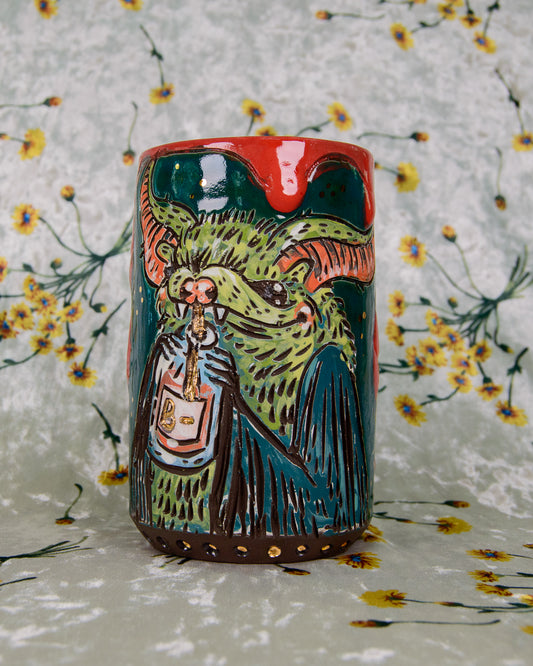 Ceramic mug with a colorful design of a bat drinking out of a blood bag with a gold straw on a floral background