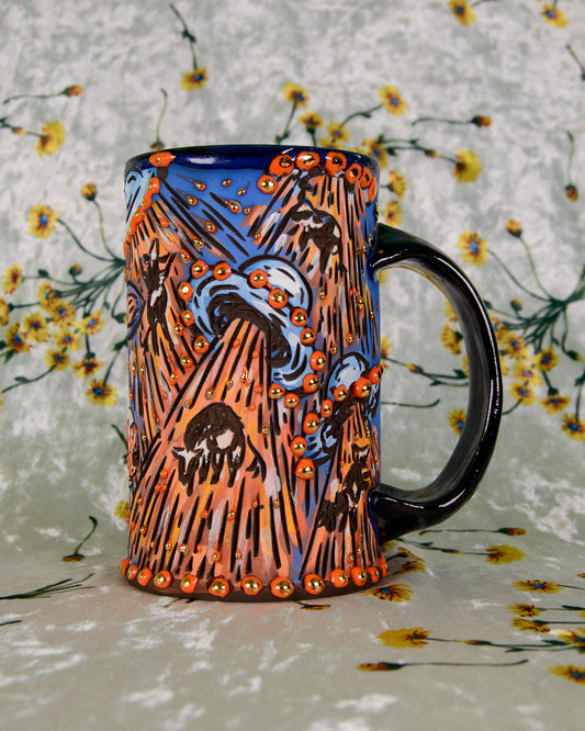 Colorful ceramic mug with orange and blue UFO alien designs and floating cows