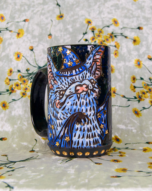 Ceramic mug with a blue  and gold bat wizard design on a floral background