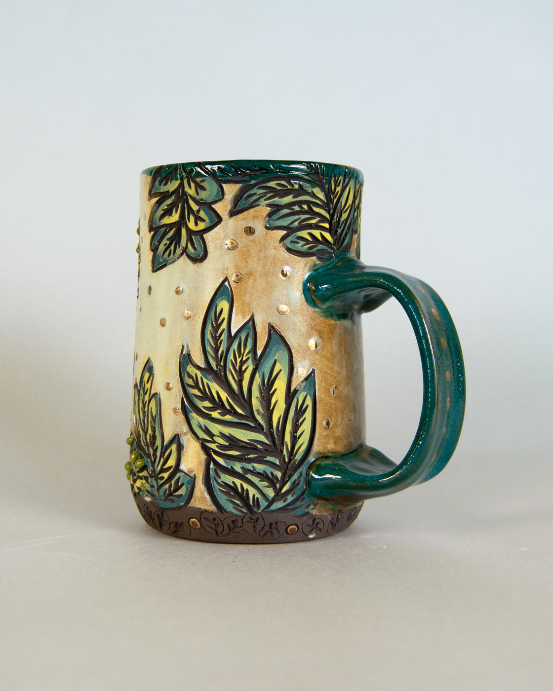 Ceramic mug with leaf design on a plain background