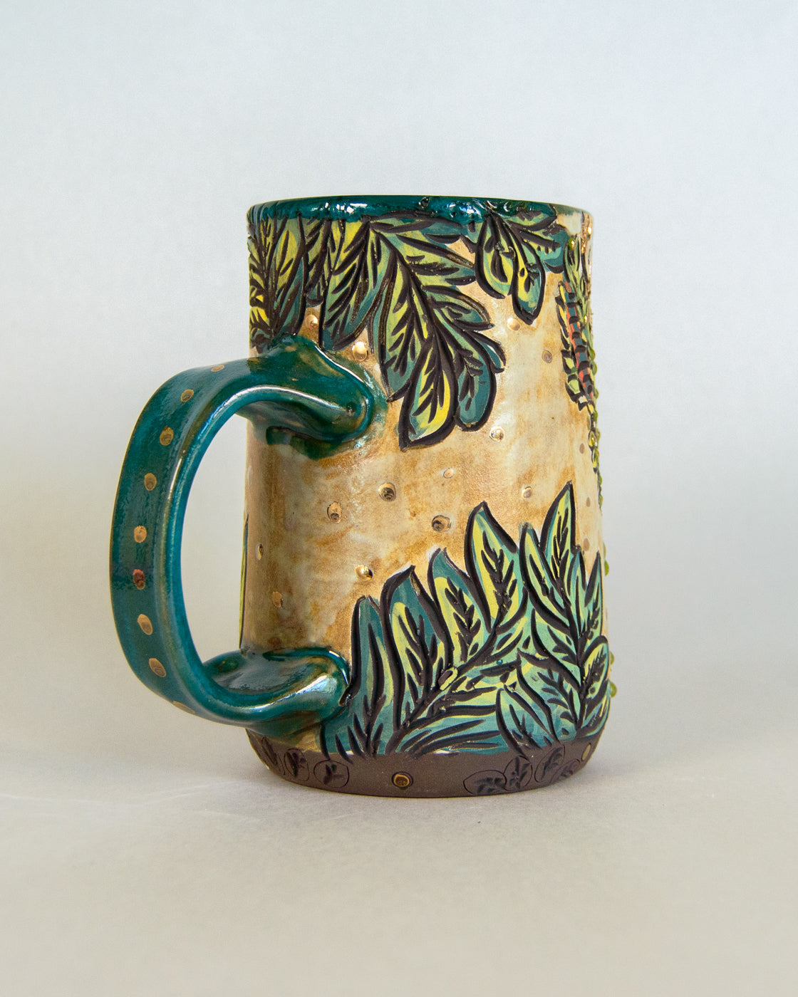 Ceramic mug with green leaf pattern on a white background