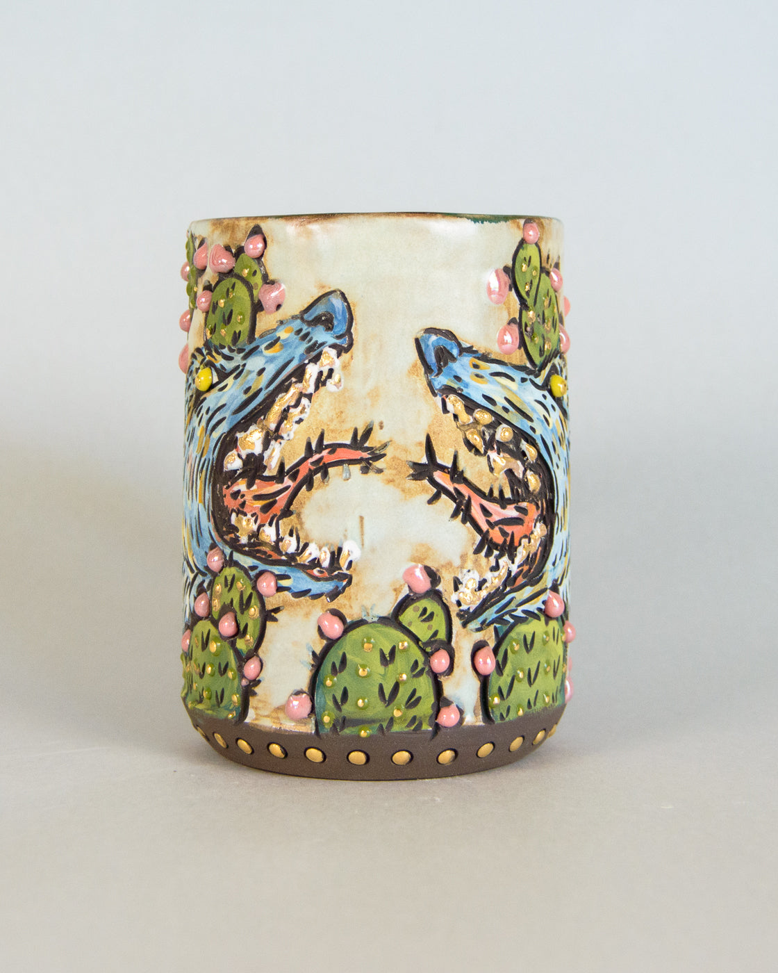 Ceramic tumbler with painted desert scene featuring coyotes and cacti on a white background